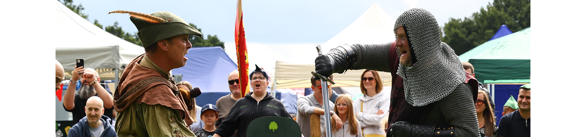 Robin Hood and knight sword fighting with a crowd