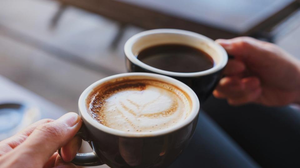 Two coffee mugs toasting.