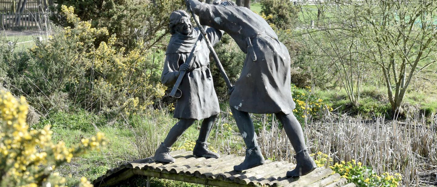 A statue depicting Robin Hood and Little John fighting on a wooden bridge